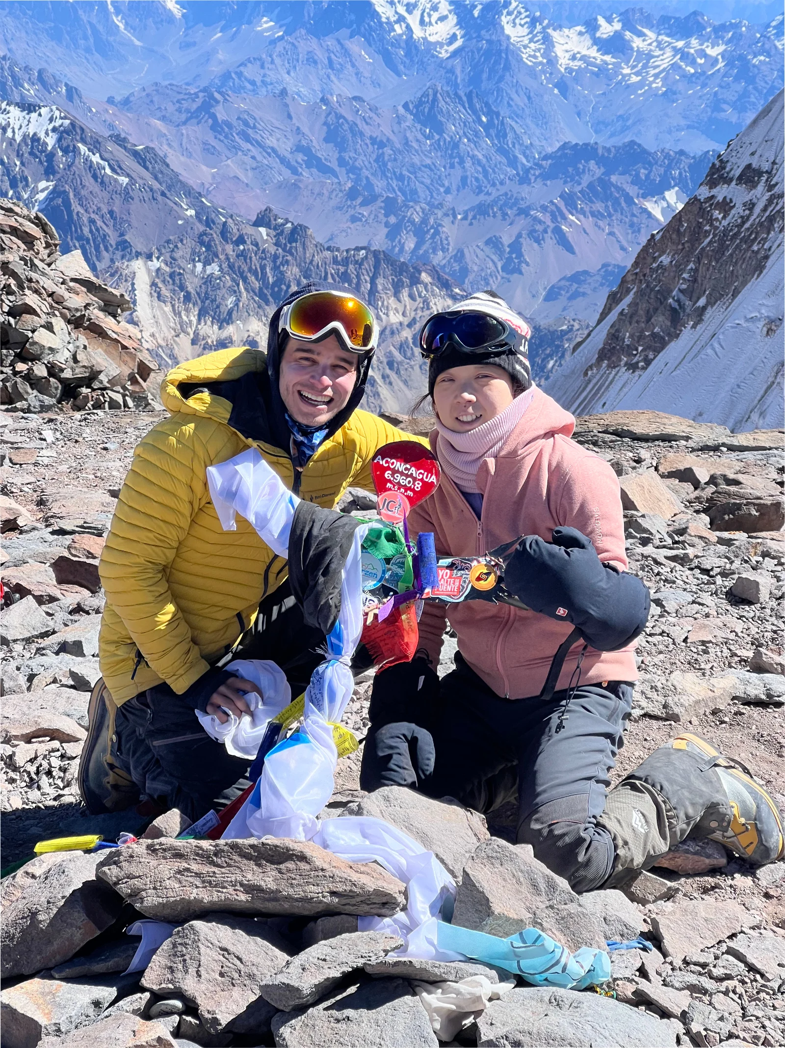Julián Kusi with a client at the Aconcagua summit holding the summit sign