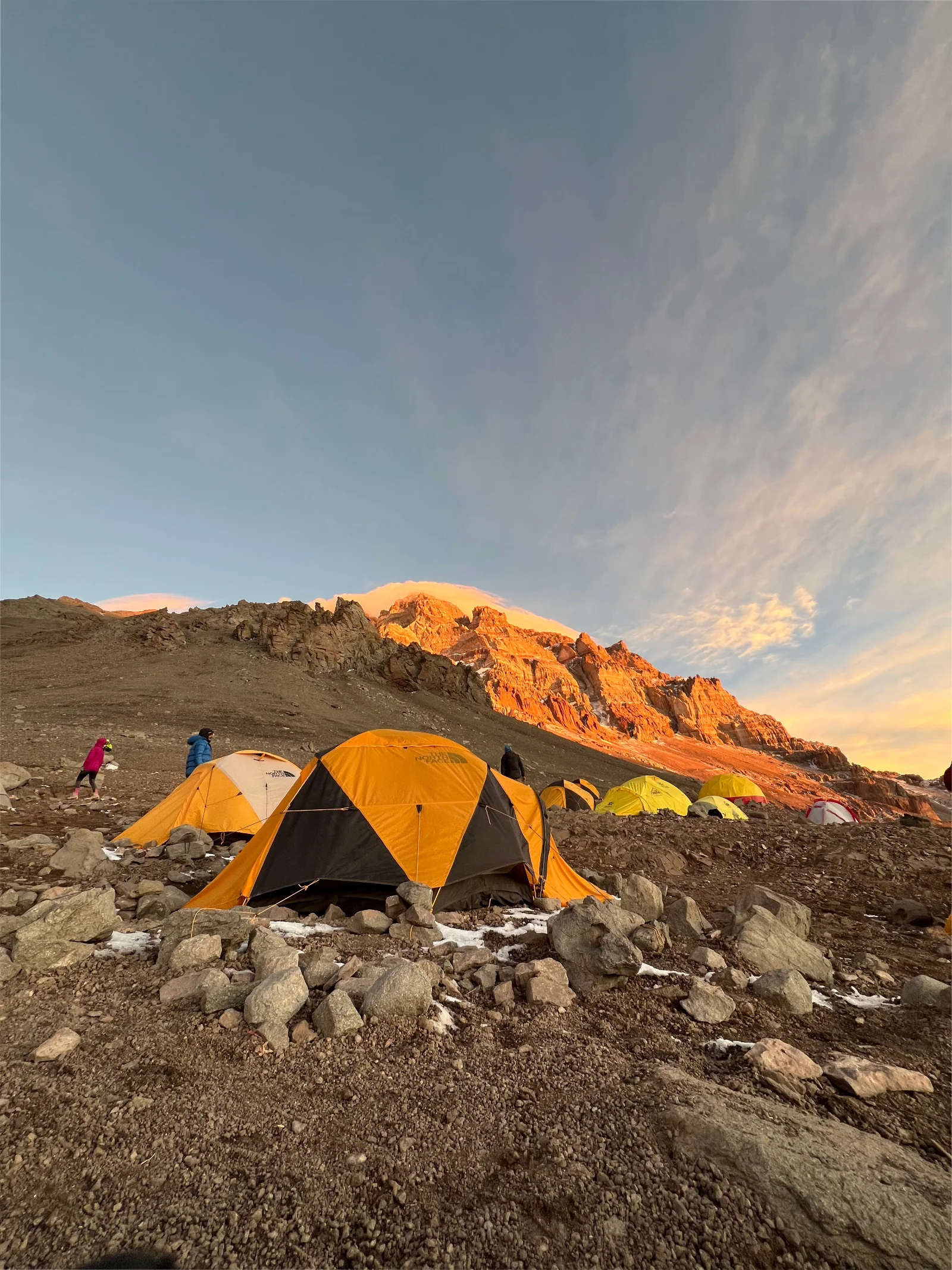 Orange expedition tents at golden hour with Aconcagua glowing behind