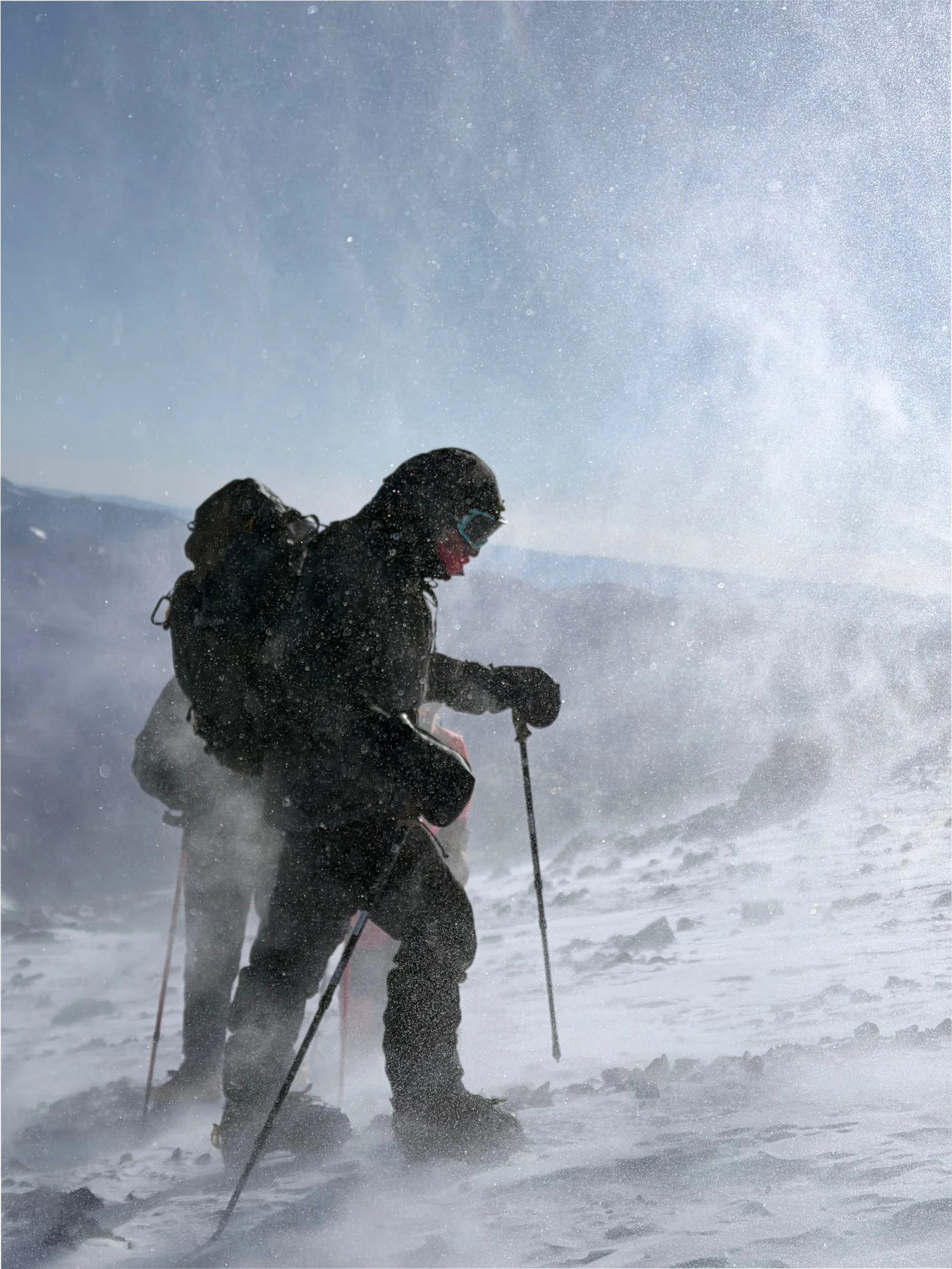 Two climbers pushing through a blizzard on the upper mountain
