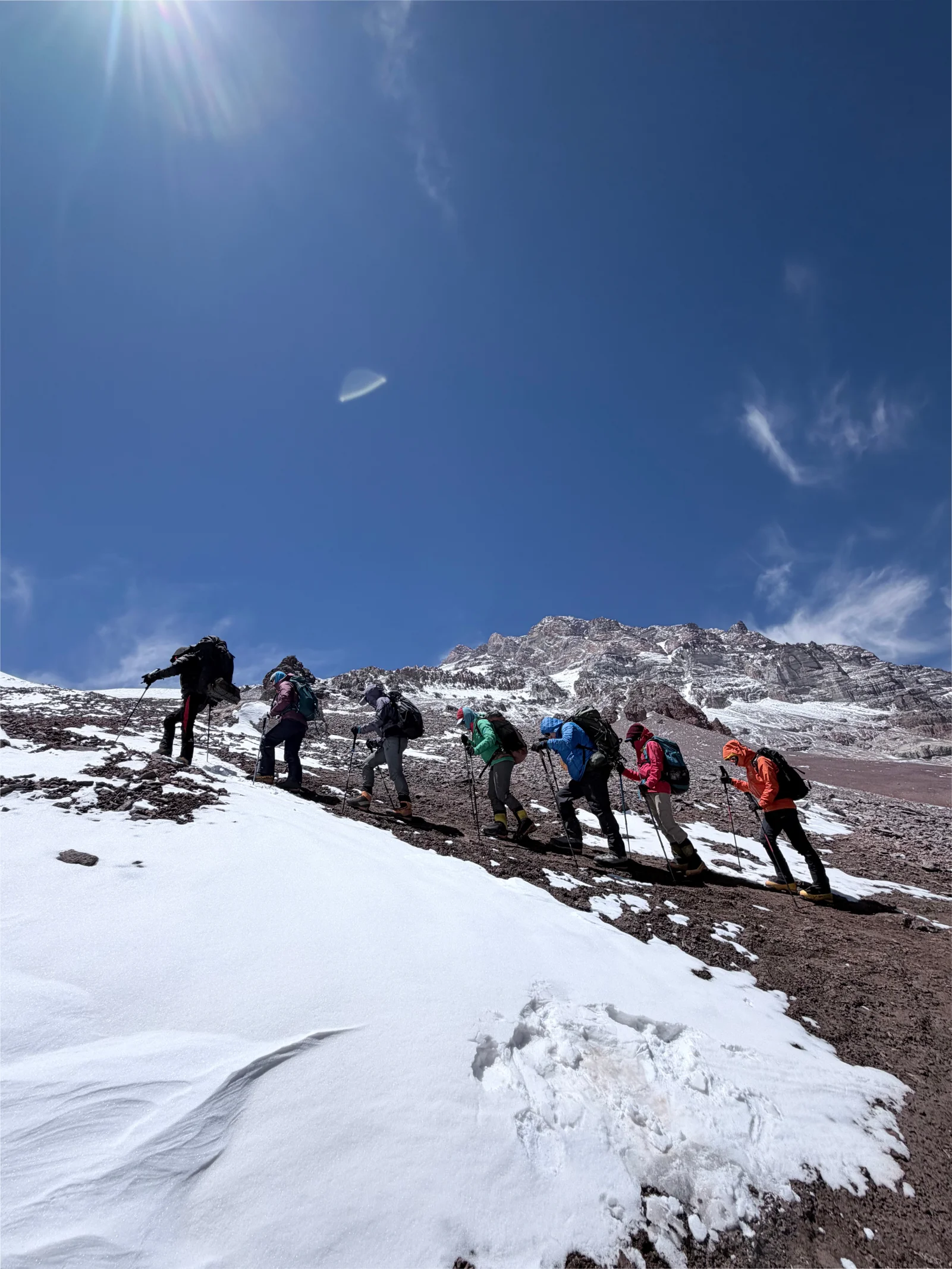 Team of six climbers ascending in a line on the high slopes